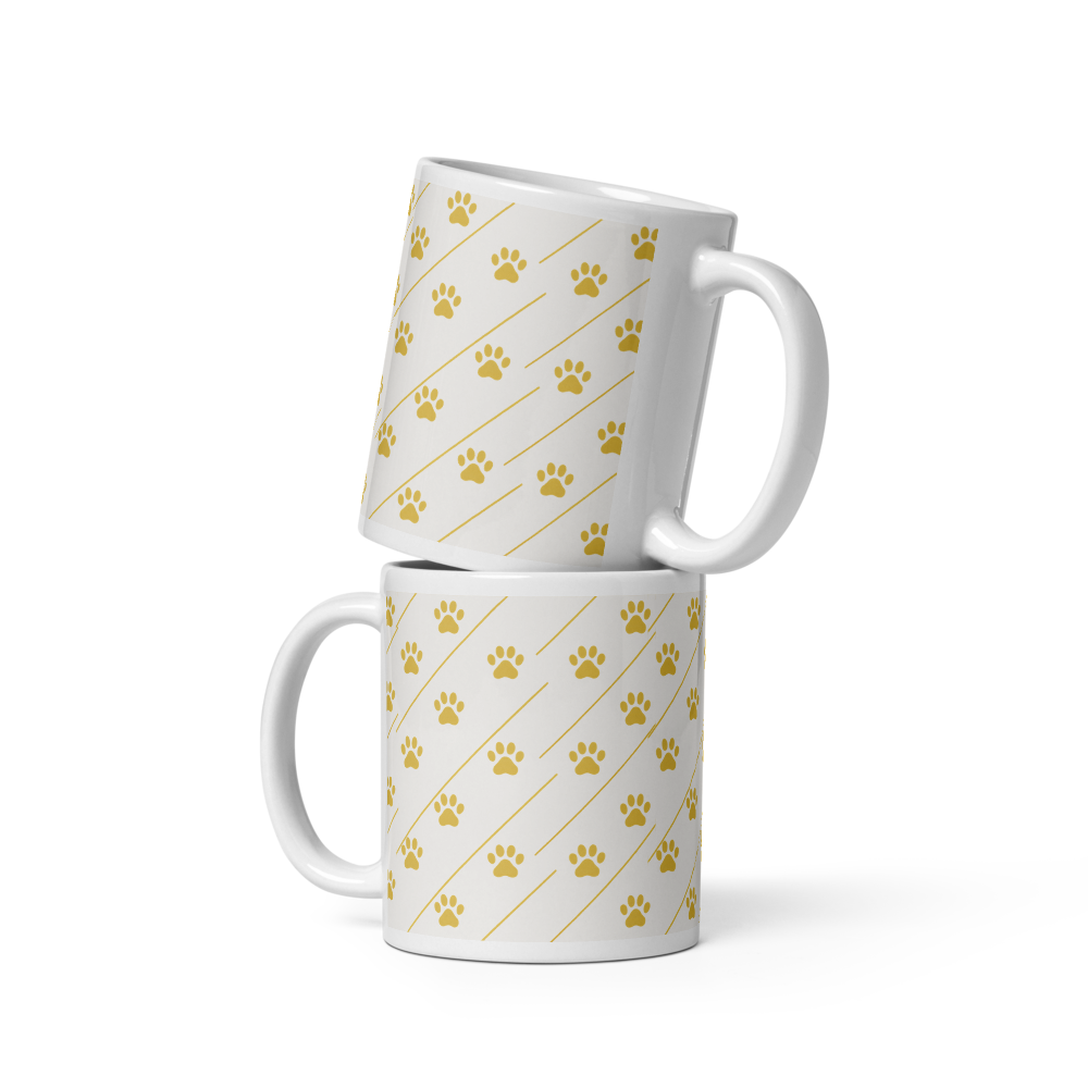 Two ivory whisper mugs with gold paw print patterns on a white background
