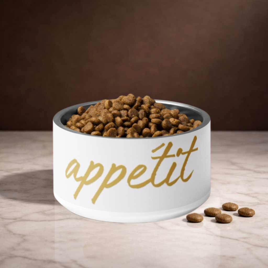 Ivory bowl with 'appétit' text filled with dog food on a wooden surface.