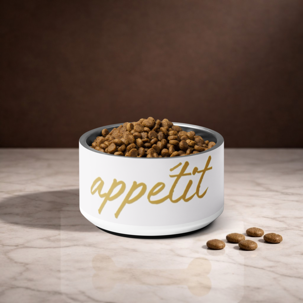 Ivory bowl with 'appétit' text filled with dog food on a marble surface.