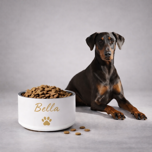 Dog sitting next to a ivory bowl labeled 'Max' filled with dog food on a gray background