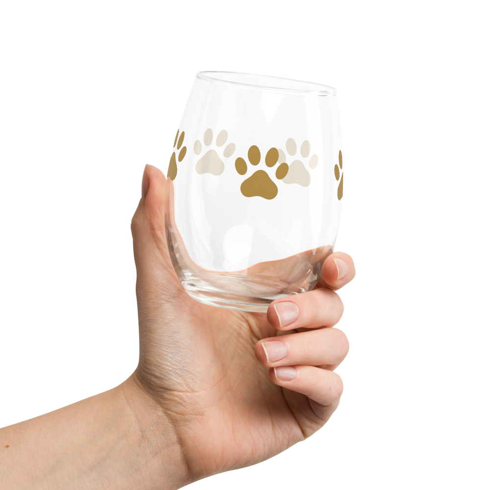 Hand holding a clear glass with paw print designs on a white background