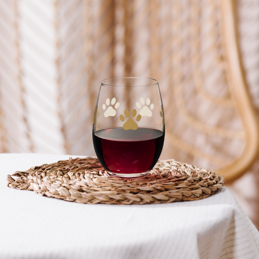 Stemless wine glass with paw prints on a woven mat