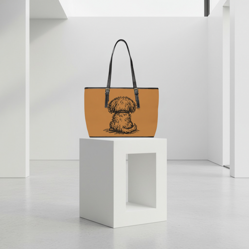 Tan handbag with a dog illustration on a white pedestal against a white background