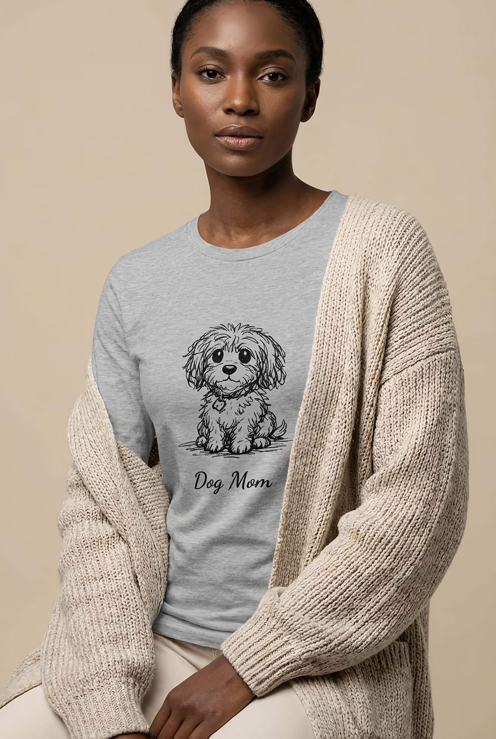 Woman wearing a gray sweater with a dog illustration and 'Dog Mom' text, sitting against a beige background.