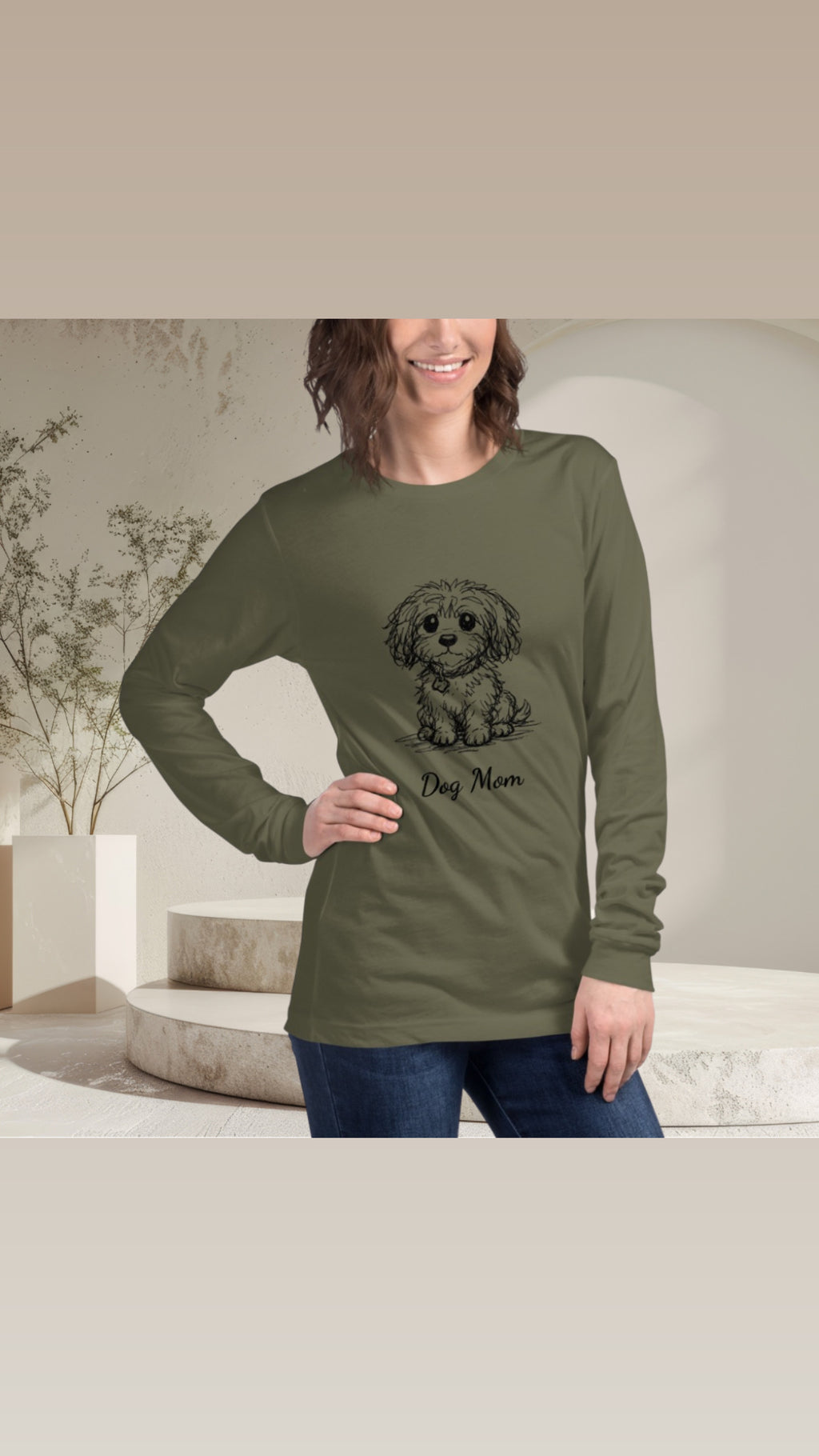 Woman wearing a green long-sleeve shirt with a dog graphic and 'Dog Mom' text in a modern indoor setting.