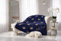 Navy blue blanket with gold crowns and 'Add Text' on a white sofa in a bright room.