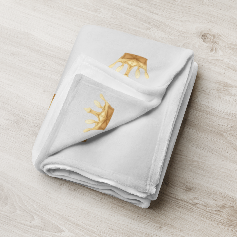 Folded towel with gold crown design on a light wooden surface