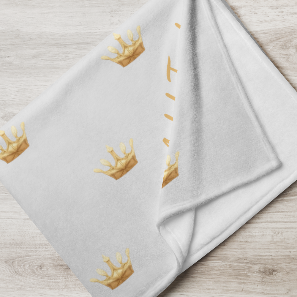 Folded white towel with gold crown patterns on a wooden surface
